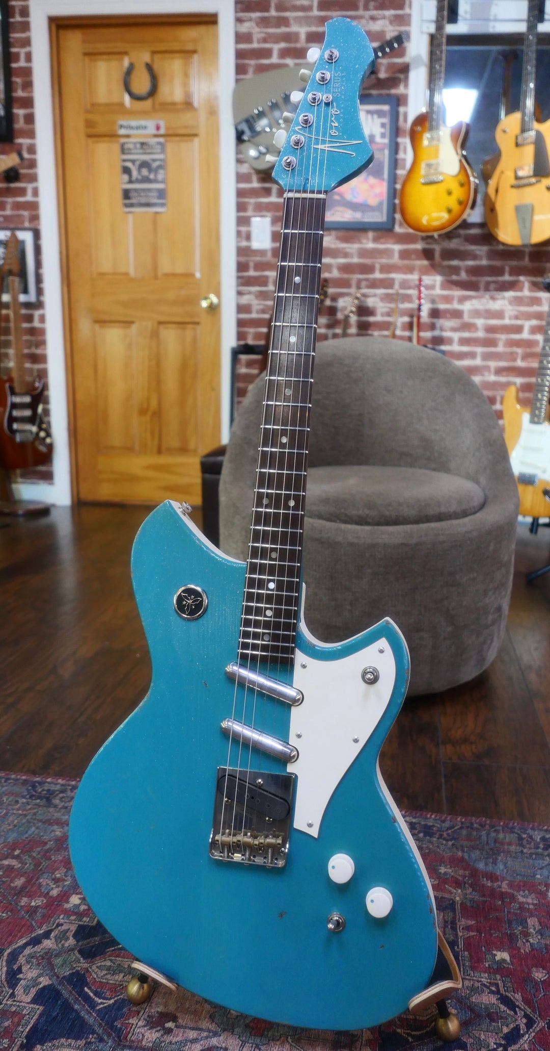 Novo Serus T Taos Turquoise guitar showcased in a cozy setting, highlighting its unique design and vibrant color.