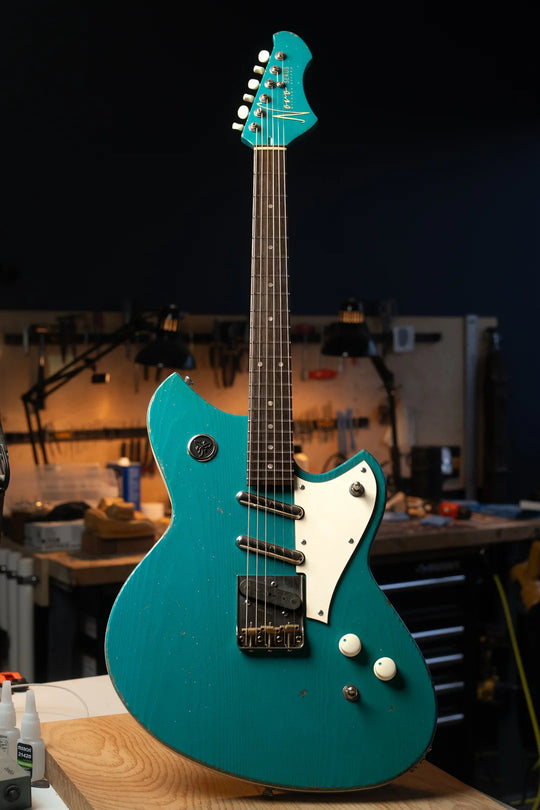 Novo Serus T Taos Turquoise guitar displayed in workshop, showcasing its unique design and craftsmanship.